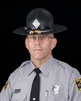 Trooper Grainger in trooper uniform and campaign hat in front of a black background